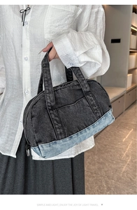 Detail of a large denim pillow bag with contrast stitching and metal strap hooks