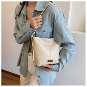 Detail of minimalist beige leather bucket bag with vertical stitching and branding