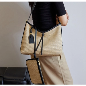 Détail d'un sac cabas en paille tissée avec bordure en cuir noir et pochette assortie
