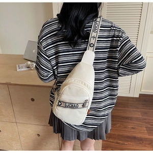 Détail du sac bandoulière en toile crème avec broderie de lettres et poches zippées multiples