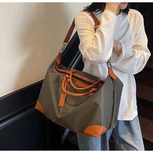 Detailed view of durable waterproof nylon travel bag with brown leather handles and straps
