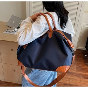 Detailed back view of a large navy canvas travel bag with brown leather trim details