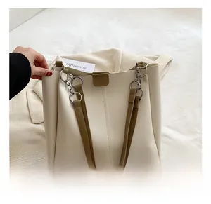 Detail of cream PU tote bag showing dark brown straps with silver metal ring connectors