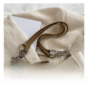 Close-up of cream PU leather tote bag with khaki strap and silver chain details