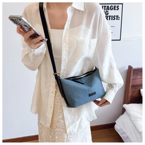 Dettaglio della borsa hobo in denim blu con tracolla in pelle nera e cerniera argentata