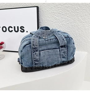 Close-up of denim Boston bag with black base and silver zipper on white surface