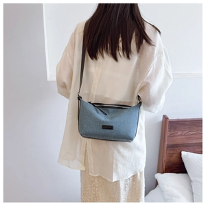 Dettaglio texture denim e toppa con logo nero su borsa a tracolla blu moda