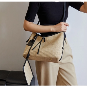 Détail du sac cabas en paille tissée avec bordure en cuir noir et mini porte-monnaie