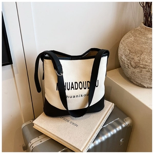Detail showing high-quality canvas and black leather stitching on a bucket crossbody bag