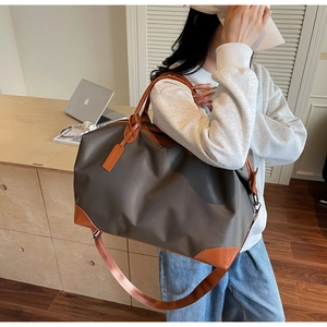 Nylon travel bag with leather trim and shoulder strap shown in a modern lifestyle setting