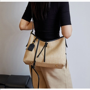 Détail d'un sac cabas en paille tressée avec garniture en cuir noir et pieds de protection