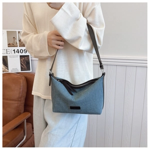 Dettaglio borsa in denim con spalline in pelle marrone e patch logo minimalista