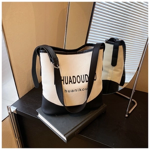 Detail of minimalist canvas tote bag showing black leather stitching and silver buckle