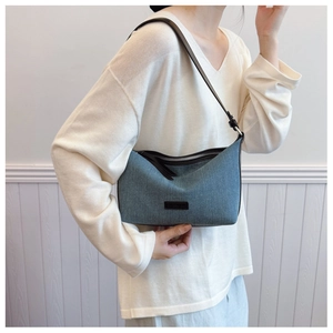 Dettaglio borsa a spalla in denim blu con tracolla in pelle marrone e finiture argentate