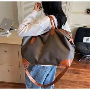 Detailed view of the large brown travel bag with leather handles and adjustable shoulder strap