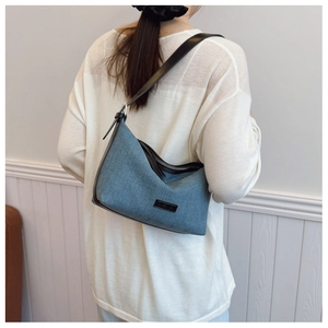 Borsa a mezzaluna in denim azzurro con tracolla nera indossata da una modella