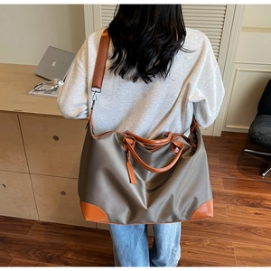 Detail view of large khaki travel tote featuring leather handles and adjustable shoulder strap