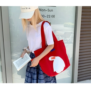 Close-up of a large red canvas tote bag with a white goose print for daily casual use