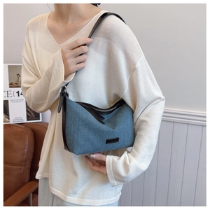 Dettaglio della borsa a mezzaluna in denim blu con finiture in pelle nera e tracolla