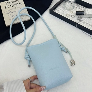 Détail du sac bandoulière bleu clair en cuir grainé avec pendentif en forme de fève