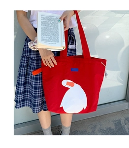 Close-up of red canvas tote bag with large white duck print and drawstring detail