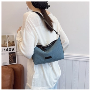 Dettaglio della borsa hobo in denim blu con tracolla regolabile e logo nero sulla parte frontale