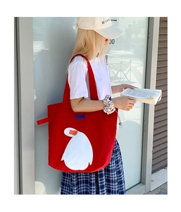 Detail of red canvas tote bag with white duck graphic and blue DUCK woven label