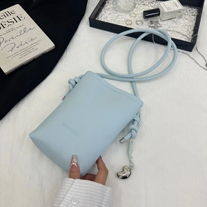 Détail du petit sac à bandoulière bleu ciel en cuir grainé avec pendentif coeur