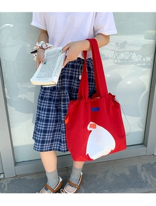 Close-up of red canvas tote bag with white cartoon duck pattern and drawstring closure