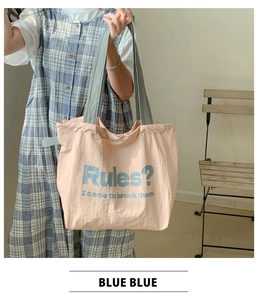 Detail der rosa Canvas-Tasche mit grauen Trägern und blauem Slogan, getragen von Model