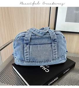 Detail of light blue denim Boston bag with white stitching on Chanel catwalk book
