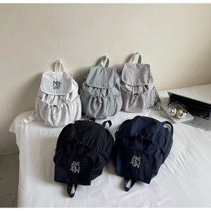 Flat lay of colorful nylon backpacks with drawstring closures and letter embroidery