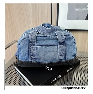 Detail view of denim bowling bag with reinforced handles on a vintage shelf display