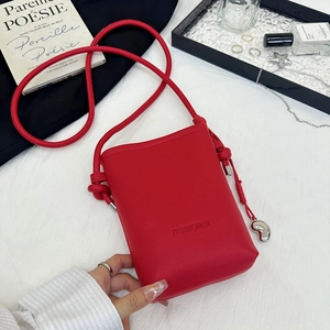 Détail du mini sac bandoulière en cuir rouge avec pendentif cœur et bandoulière nouée