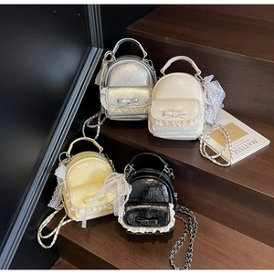 Close-up of four colors of ruffled lace backpacks with bow details and pearl charms