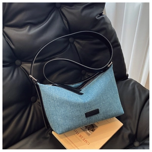 Dettaglio ravvicinato della borsa a tracolla in denim blu con cinturino in pelle nera