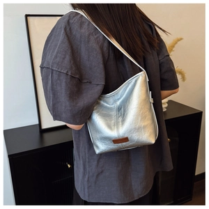 Metallic silver bucket bag with brown logo label shown on model shoulder