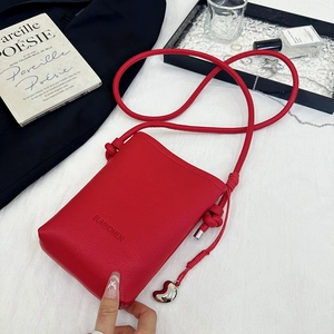 Détail du petit sac bandoulière rouge avec pendentif cœur et logo SUNWOMEN
