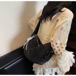 Detail of black pleated hobo bag with silver zipper and spiral metal charm accessory