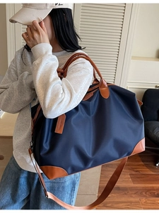 Large dark blue waterproof nylon travel bag with brown leather handles and shoulder strap