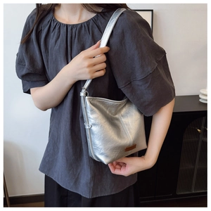Silver metallic leather bucket bag detail with a small brown leather tag and thin strap