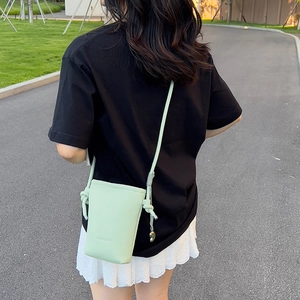 Détail du sac de téléphone vert menthe avec bandoulière nouée et pendentif