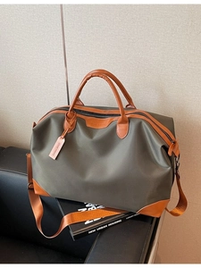 Olive green large capacity travel bag with leather trim on a leather sofa