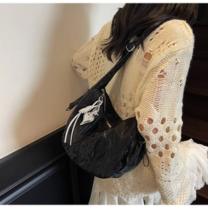 Close-up of black hobo bag with pleated texture and silver heart butterfly charms