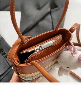 Dettaglio della borsa a secchiello in paglia color-block con zip e ciondolo orso