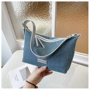 Dettaglio borsa a tracolla in denim blu con fibbie argentate e cinturino in pelle