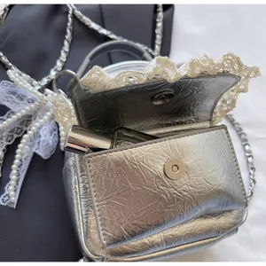 Detail of silver pleated crossbody bag with lace trim showing lipstick storage capacity