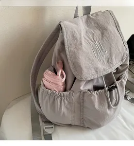 Detail of grey nylon backpack side pocket showing a pink umbrella for storage capacity