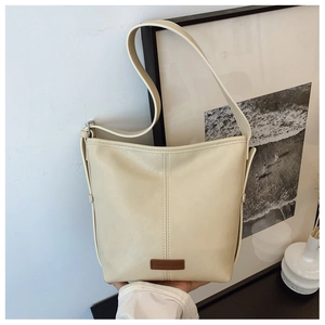 Detail of cream white PU leather bucket bag with vertical stitching and square brand logo