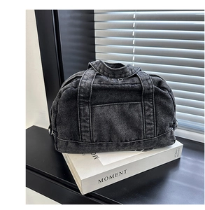 Detail of a large denim pillow tote bag with sturdy handles and washed texture